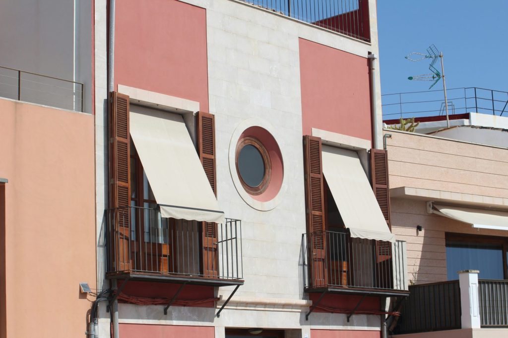 building with two balconies, a round window, and a retractable awning